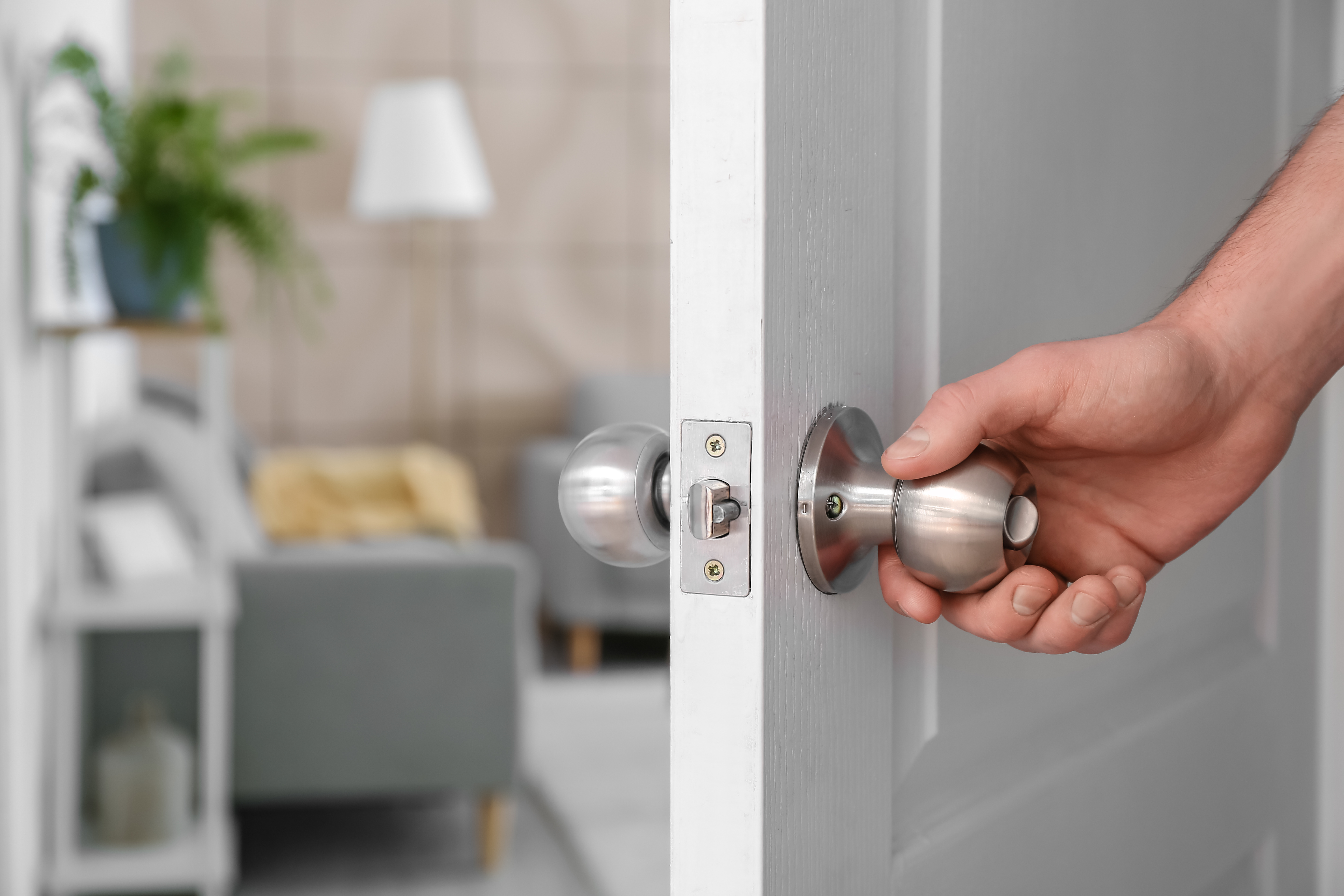 Une main d'un homme qui ouvre une porte de maison. © Pixel-Shot | Adobe Stock